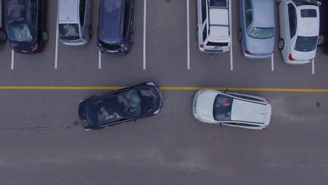 Two-cars-trying-to-get-into-the-same-parking-spot,-4k-drone-direct-overhead