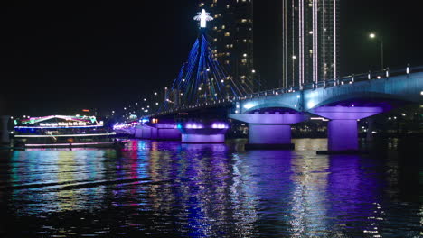 Filmische-Nachtansicht-Der-Tran-Thi-Ly-Brücke-über-Den-Han-Fluss-Und-Kreuzfahrtschiff-In-Der-Vietnamesischen-Stadt-Da-Nang,-Beleuchtet-Mit-Lichtern