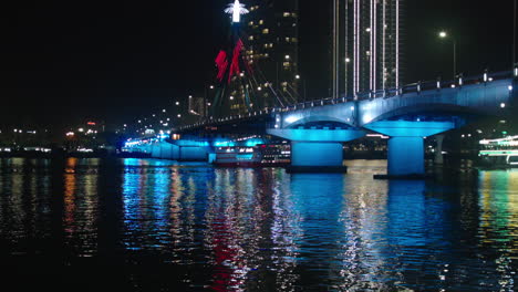 Filmische-Nachtansicht-Der-Tran-Thi-Ly-Brücke-über-Den-Han-Fluss-Und-Kreuzfahrtschiff-In-Der-Vietnamesischen-Stadt-Da-Nang,-Beleuchtet-Mit-Lichtern