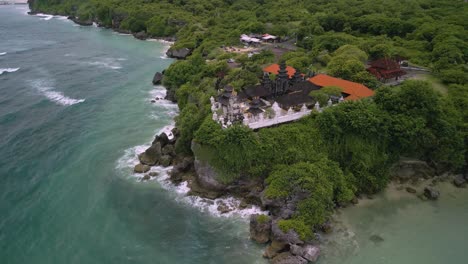 Drone-panning-shot-of-a-giant-temple-complex-between-the-green-nature-on-a-cliff