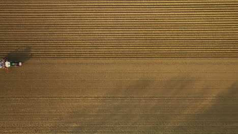 Vista-De-ángulo-Alto-De-Un-Dron-De-Un-Tractor-Que-Conduce-Sobre-Un-Campo-De-Cultivo-De-Patatas