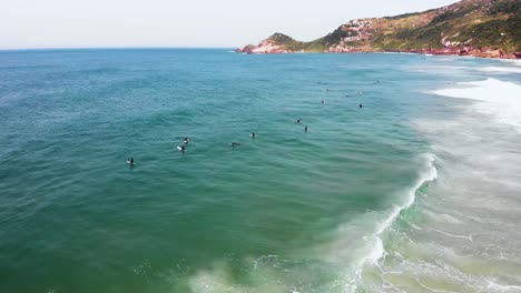 Surfers-in-the-sea,-behind-the-waves-at-the-shore-of-Floripa,-Brazil