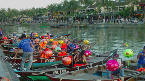 Parked-wooden-traditional-jukung-boats-with-riders-in-the-river-of-ancient-town-of-Hoi-An,-Vietnam