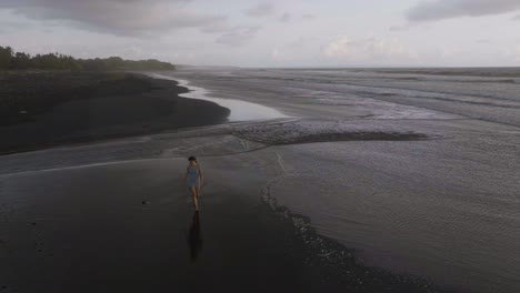 Mujer-Caminando-En-La-Impresionante-Playa-Exótica-De-Arena-Negra-En-Lovina,-Bali