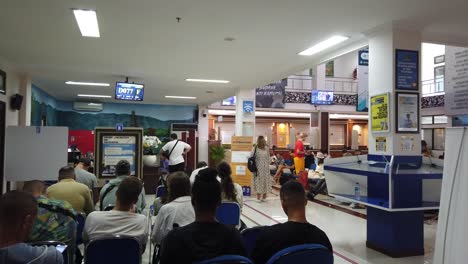 Einwanderungsbehörde-In-Jimbaran,-Bali,-Touristen-Warten-Auf-Visa--Und-Migrationsdienste,-Eingangshalle,-Sitzende-Menschen,-Ngurah-Rai-Kantor,-Badung