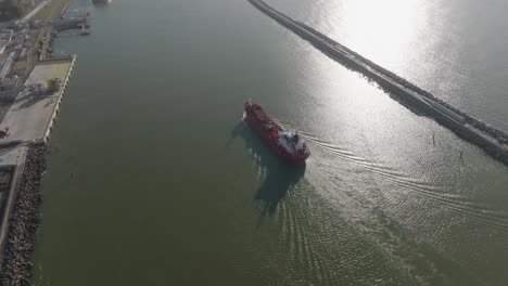 Aerial-view-a-red-cargo-ship-is-sailing-in-the-port-area,-also-known-as-the-Curonian-Lagoon