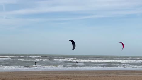 Slow-motion-wide-shot-of-surfing-kite-surfer-on-waves-of-North-Sea-during-sunny-day-in-Netherlands