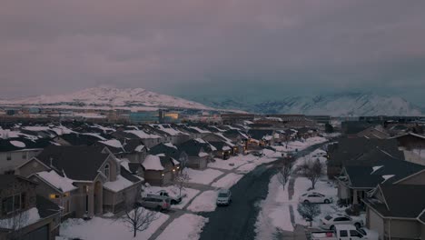 Snow-day-in-a-suburban-neighborhood-in-a-valley-below-the-mountains---ascending-aerial-reveal
