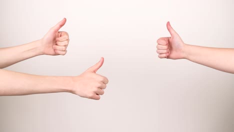Four-thumbs-up-coming-in-frame-one-at-the-time-on-a-white-background