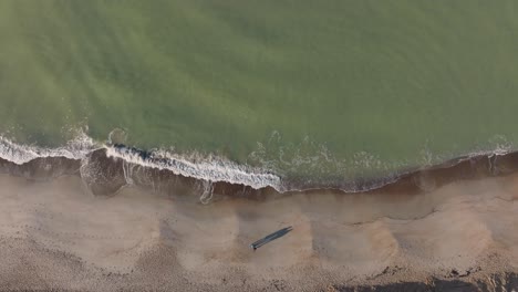 Luftaufnahme:-Zwei-Menschen-Laufen-Langsam-über-Den-Sand,-Und-An-Einem-Kalten-Herbstmorgen-Spülen-Meereswellen-Das-Ufer-Des-Strandes