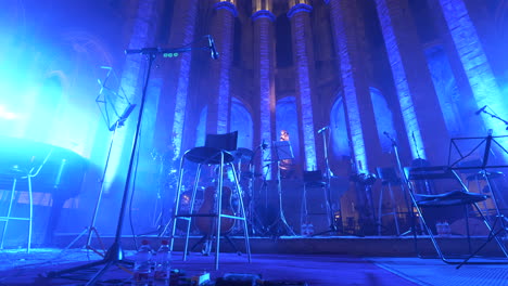Musical-instrument-setup-on-stage-in-Barcelona-Cathedral-lit-by-neon-lights,-motion-view