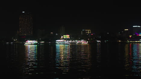 Cruise-lit-with-colorful-lights-sailing-across-Han-river-in-Da-Nang-city,-Vietnam,-Wide-angle-shot