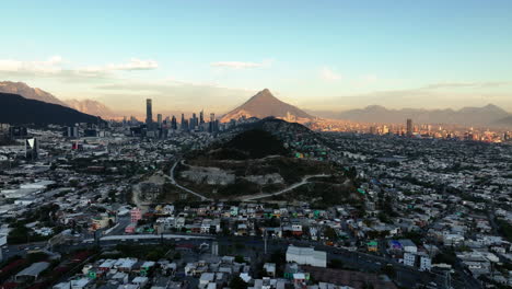 Aerial-view-rising-over-the-cityscape-of-Monterrey,-sunset-in-Nuevo-Leon,-Mexico