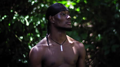 African-American-man-wearing-a-black-headscarf-with-defocused-green-vegetation-background-behind