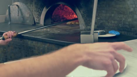 Cook-taking-pizza-out-of-the-oven-and-placing-it-on-a-plate