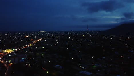 Panoramic-aerial-view-over-a-illuminated-Etoug-ebe-neighborhood-in-the-city-of-Yaounde,-dusk-in-Cameroon
