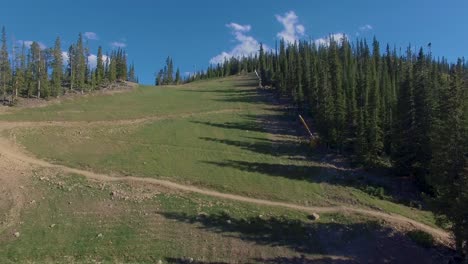 Mountain-biker-rides-and-jumps-down-switchback-trail-in-Keystone,-Colorado