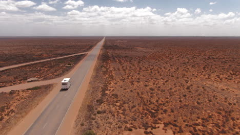 Campervan-driving-on-an-empty-long-straight-road-in-a-barren-environment-in-South-Australia
