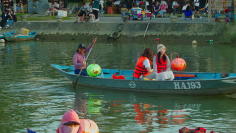 Young-women-tourist-enjoying-wooden-traditional-boat-tour-in-the-ancient-town-of-Hoi-An-in-the-evening,-Vietnam