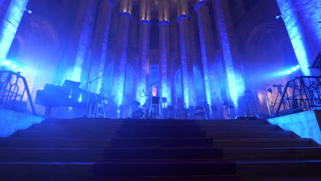 Musician-setup-on-glowing-stage-of-Barcelona-Cathedral,-dolly-forward-view