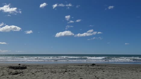 Wolken-Erscheinen-Fast-Bewegungslos,-Während-An-Einem-Schönen-Sommertag-Kleine-Wellen-In-Den-Sandstrand-Rollen-–-Sumner-Beach