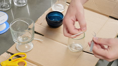 Using-a-hot-glue-gun-to-hold-the-wick-in-a-jar-for-candle-making