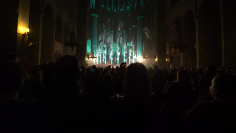 Silhouette-of-people-standing-and-clapping-at-concert-in-Barcelona-Cathedral,-back-view