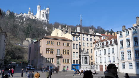 People-strolling-in-streets-of-Lyon-city-with-Notre-Dame-de-Fourvière-basilica-on-background