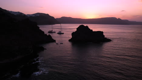 Puesta-De-Sol-Púrpura-Sobre-La-Isla-De-Santorini-Grecia-Y-Barcos-En-El-Mar-Egeo,-Vista-Aérea