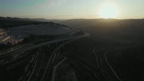 Aerial-parallax-shot-of-sunset-over-forest-and-highway