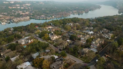 Suburban-Neighborhood-Homes-in-Tarrytown,-Austin-Texas-overlooking-Lake-Austin-Aerial-pull-away-and-tilt-up-at-sunrise-in-4k