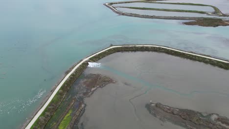 Sea-water-is-filling-salt-marshes-in-the-Île-de-Ré-at-village-of-Loix-in-Western-France,-Aerial-approach-shot
