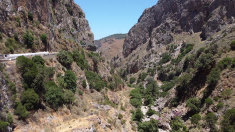 Aerial-view-through-Topolia-gorge,-canyon-road-and-lush-mountain-valley,-Crete,-Greece