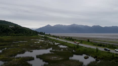 4K-Luftdrohnenaufnahmen-Eines-Feuchtgebiets-In-Alaska-Entlang-Der-Autobahn-Mit-Fahrenden-Autos-Und-Lastwagen