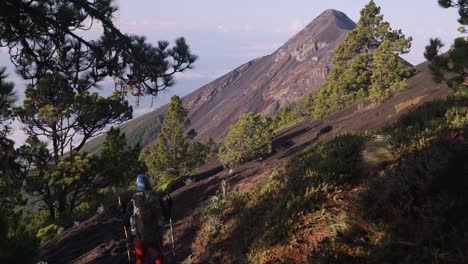 Hiker-walking-down-with-a-beautiful-view-of-a-volcano-in-the-backgorund