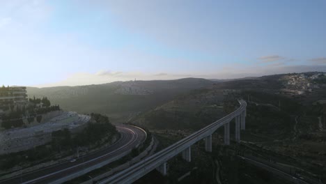 Aerial-shot-of-sunset-over-a-forest-and-railway-bridge