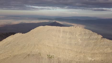 Wanderer-Auf-Dem-Gipfel-Des-Mount-Nebo-In-Salt-Lake-City,-Utah,-Mit-Dramatischem-Goldenem-Stundenlicht,-Das-über-Die-Landschaft-Fällt-–-Luftbild