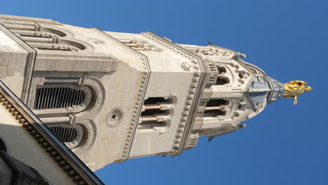 Golden-statue-of-Virgin-Mary-atop-Basilica-of-Notre-Dame-de-Fourviere-bell-tower,-Lyon---vertical-video-against-blue-sky