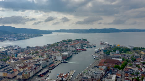 Beautiful-drone-shot-from-Bergen,-Norway-with-moving-clouds,-boats,-traffic-and-rays-of-sun-peaking-through-the-clouds