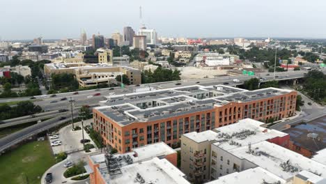 San-Antonio-Pearl-District-aerial-view-of-downtown,-pan-right-orbit-over-freeway-commuters-and-apartment-complex-near-riverwalk-in-4k