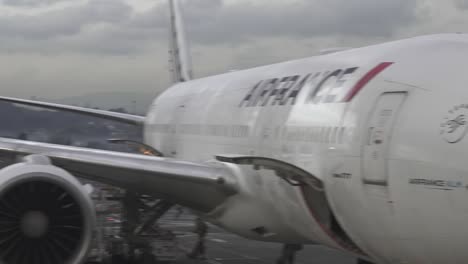 Air-France-777-jet-parked-at-airport-gate-while-loading-cargo,-Pan-left-shot
