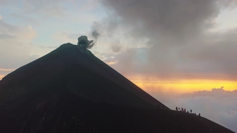 Volcán-En-Erupción-Mientras-Un-Grupo-De-Personas-Está-De-Pie-En-Una-Cresta-Cercana