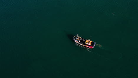 Die-Herauszoomende-Drohnenaufnahme-Eines-Fischerbootes-Beginnt,-Während-Menschen-Aus-Nächster-Nähe-An-Deck-Arbeiten