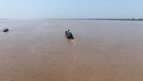 A-car-secured-to-a-handmade-raft-for-transport-across-Benue-River-by-Ibi-Town,-Nigeria---aerial-follow