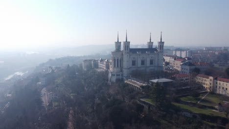 Luftaufnahme-Der-Basilika-Notre-Dame-De-Fourvière-Mit-Blick-Auf-Das-Dunstige-Lyon,-Die-Skyline-Der-Französischen-Stadt-Bei-Sonnenaufgang