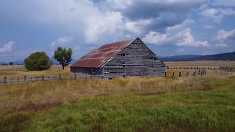 Drone-footage-over-a-rustic-vintage-abandoned-barn-in-a-field-in-the-summertime