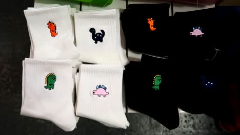 Revealing-shot-of-embroidered-dinosaurs-on-socks-on-sale-in-a-street-market-in-London