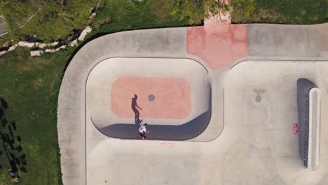Uy-Skatet-Am-Bowl-–-Großer-Skatepark-Mit-Gras-Und-Bäumen-Drumherum-–-Blick-Von-Oben-Nach-Unten