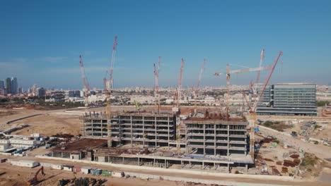 An-office-building-under-construction-with-many-cranes-on-it---pullback-rotation-shot