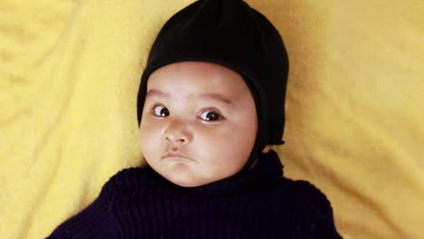 Niño-Pequeño-Vestido-De-Negro-Que-Miente-Con-Una-Linda-Expresión-Facial-En-El-Interior-Desde-El-ángulo-Superior